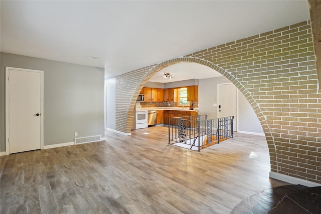 2515 Glenbrook Dr, Des Moines, IA 50316 - living room with light wood-type flooring, arched walkways, and brick wall