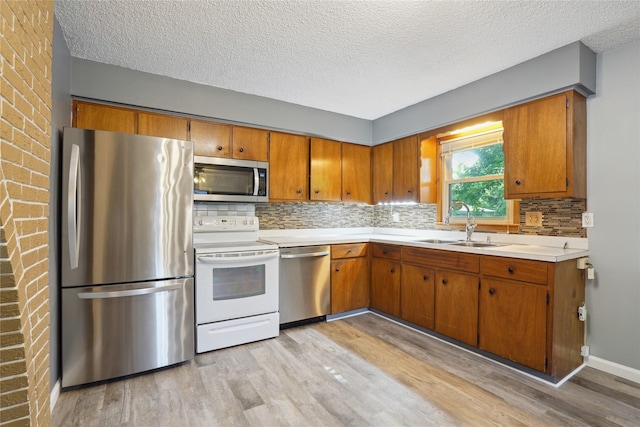 2515 Glenbrook Dr, Des Moines, IA 50316 - kitchen with stainless steel appliances, light wood-style flooring, brown cabinetry, light countertops, and a textured ceiling