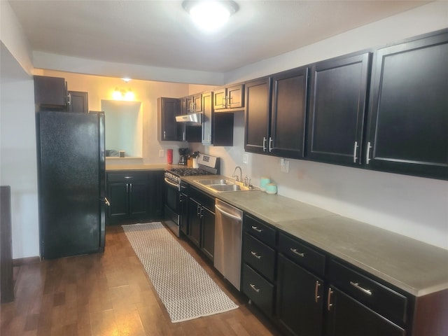 707 E 27th St S, Newton, IA 50208 - kitchen with appliances with stainless steel finishes, dark wood-style flooring, dark cabinetry, and under cabinet range hood