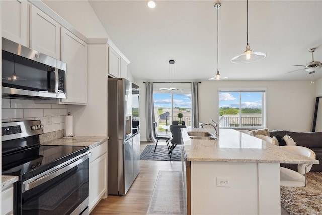 2814 Long Ave, Van Meter, IA 50261 - kitchen with appliances with stainless steel finishes, open floor plan, decorative backsplash, white cabinets, and light wood-style floors