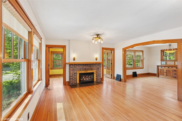 3320 SW 12th St, Des Moines, IA 50315 - unfurnished living room with light wood-type flooring, a brick fireplace, healthy amount of natural light, and a chandelier