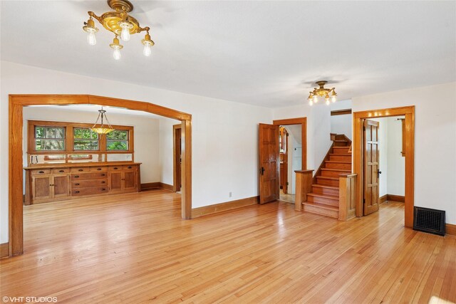 3320 SW 12th St, Des Moines, IA 50315 - unfurnished living room featuring a chandelier, light wood finished floors, and stairs