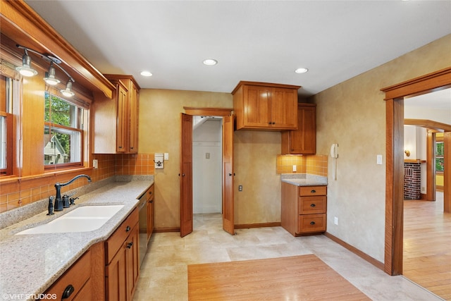3320 SW 12th St, Des Moines, IA 50315 - kitchen with backsplash, light stone counters, brown cabinets, recessed lighting, and stainless steel dishwasher