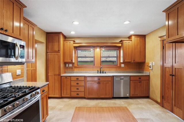 3320 SW 12th St, Des Moines, IA 50315 - kitchen with appliances with stainless steel finishes, brown cabinets, decorative backsplash, and recessed lighting