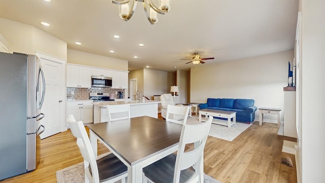 469 SE Hollow Ct, West Des Moines, IA 50265 - dining space with light wood finished floors, a ceiling fan, a chandelier, and recessed lighting