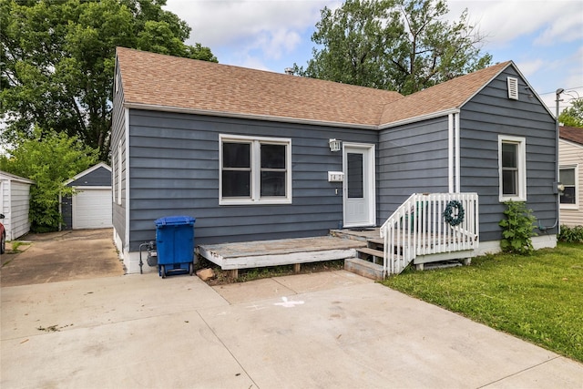 1428 E Tiffin Ave, Des Moines, IA 50316 - view of front of property with roof with shingles, a garage, an outbuilding, and a front lawn