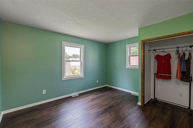 1428 E Tiffin Ave, Des Moines, IA 50316 - unfurnished bedroom featuring multiple windows, a closet, dark wood-style flooring, and a textured ceiling