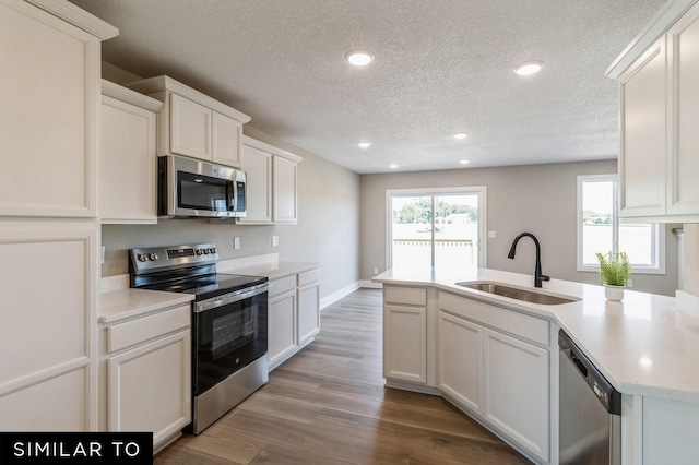 6502 NE Kendall Ave, Pleasant Hill, IA 50327 - kitchen with appliances with stainless steel finishes, a textured ceiling, light countertops, recessed lighting, and wood finished floors