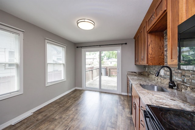 1012 28th St, Des Moines, IA 50311 - kitchen with brown cabinetry, dark wood-type flooring, light stone countertops, decorative backsplash, and black microwave