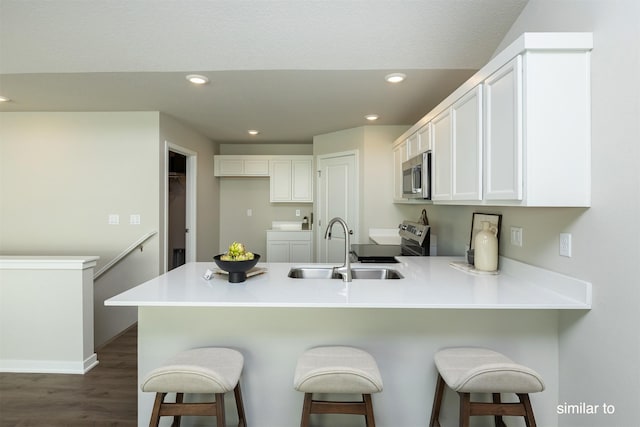 725 Linden St, Carlisle, IA 50047 - kitchen featuring stainless steel appliances, a peninsula, white cabinetry, recessed lighting, and dark wood finished floors