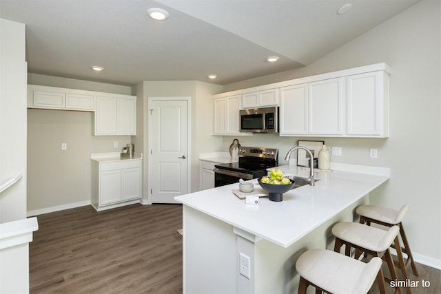 735 Linden St, Carlisle, IA 50047 - kitchen featuring appliances with stainless steel finishes, a peninsula, white cabinets, a breakfast bar, and recessed lighting