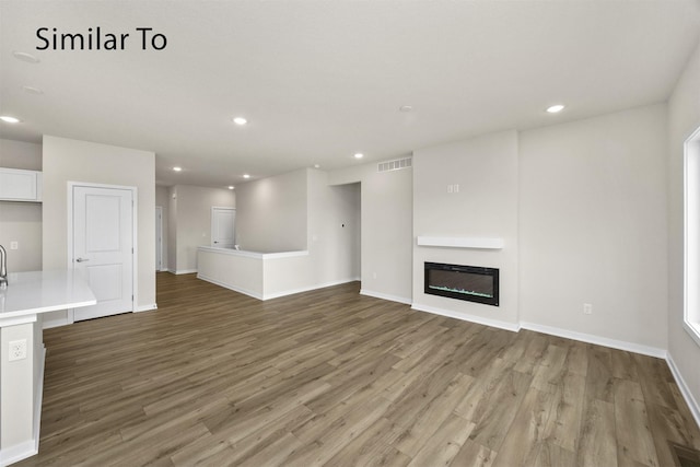 16732 Walnut Meadows Cir, Urbandale, IA 50323 - unfurnished living room with light wood-style floors, recessed lighting, and a glass covered fireplace