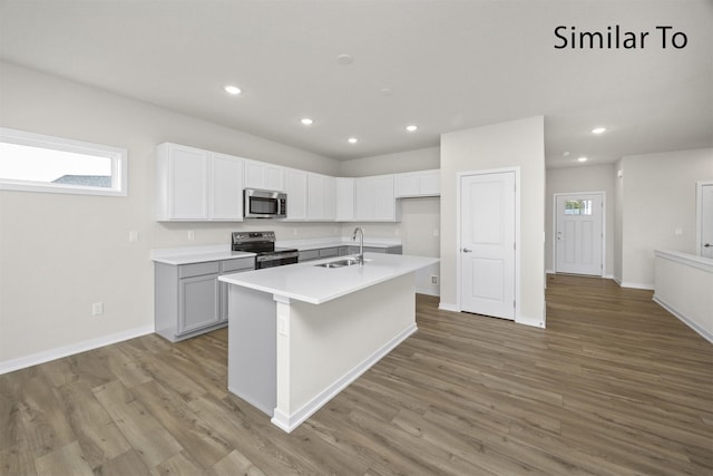 16732 Walnut Meadows Cir, Urbandale, IA 50323 - kitchen with stainless steel appliances, recessed lighting, light wood-style flooring, a kitchen island with sink, and light countertops
