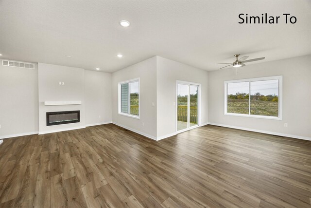 16732 Walnut Meadows Cir, Urbandale, IA 50323 - unfurnished living room featuring wood finished floors, ceiling fan, a glass covered fireplace, and recessed lighting