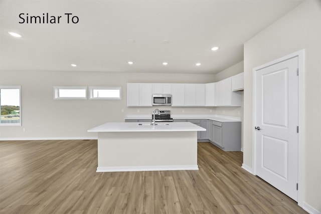 16732 Walnut Meadows Cir, Urbandale, IA 50323 - kitchen with appliances with stainless steel finishes, light wood-style floors, a kitchen island with sink, light countertops, and recessed lighting