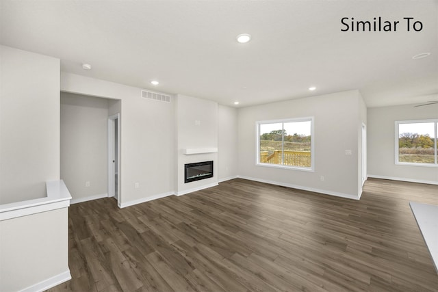 16732 Walnut Meadows Cir, Urbandale, IA 50323 - unfurnished living room with dark wood-type flooring, a glass covered fireplace, and recessed lighting