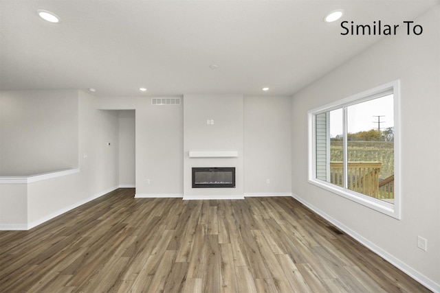 16738 Walnut Meadows Cir, Urbandale, IA 50323 - unfurnished living room featuring recessed lighting, a glass covered fireplace, and wood finished floors