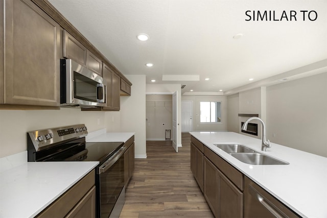 2212 Legacy Dr, Norwalk, IA 50211 - kitchen with appliances with stainless steel finishes, wood finished floors, light countertops, recessed lighting, and dark brown cabinetry