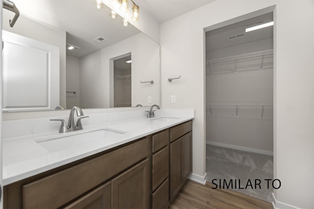 2212 Legacy Dr, Norwalk, IA 50211 - bathroom with double vanity, wood finished floors, and a spacious closet
