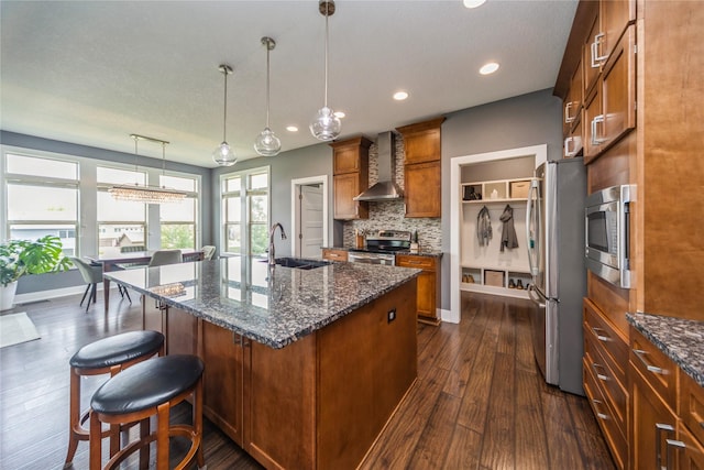 16823 Prairie Dr, Clive, IA 50325 - kitchen featuring wall chimney range hood, appliances with stainless steel finishes, brown cabinetry, dark wood-style floors, and backsplash