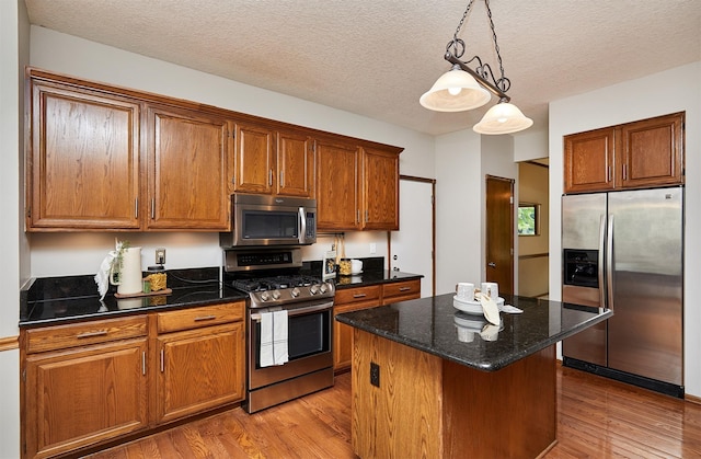 2216 NW 136th St, Clive, IA 50325 - kitchen with stainless steel appliances, light wood-type flooring, a kitchen island, brown cabinets, and a textured ceiling