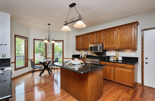 2216 NW 136th St, Clive, IA 50325 - kitchen featuring stainless steel appliances, brown cabinetry, wood-type flooring, pendant lighting, and a textured ceiling