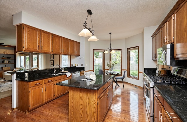 2216 NW 136th St, Clive, IA 50325 - kitchen featuring appliances with stainless steel finishes, light wood-type flooring, a kitchen island, plenty of natural light, and a textured ceiling