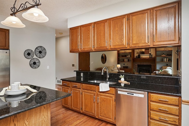 2216 NW 136th St, Clive, IA 50325 - kitchen with appliances with stainless steel finishes, brown cabinetry, light wood-style floors, dark stone counters, and a textured ceiling