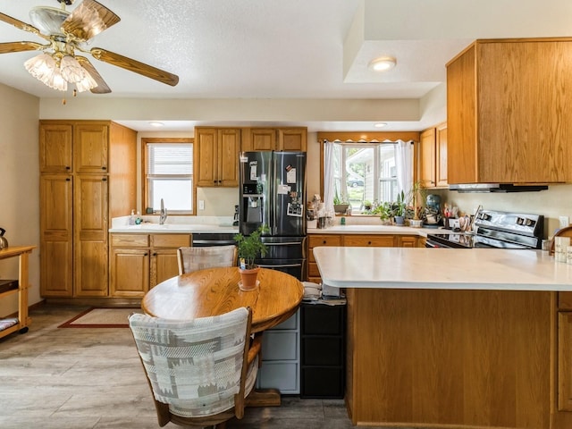 312 N J St, Indianola, IA 50125 - kitchen with electric range, black fridge, light countertops, brown cabinets, and a peninsula