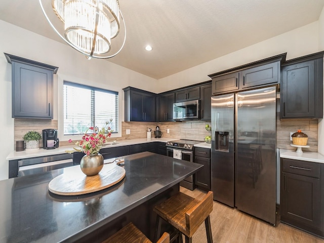 2502 Blooming Heights Dr, Norwalk, IA 50211 - kitchen with stainless steel appliances, a breakfast bar area, backsplash, light wood-style flooring, and hanging light fixtures