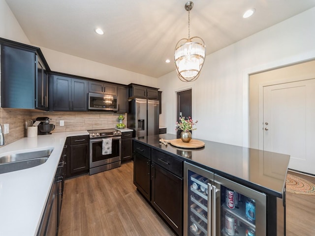 2502 Blooming Heights Dr, Norwalk, IA 50211 - kitchen featuring appliances with stainless steel finishes, beverage cooler, wood finished floors, backsplash, and a chandelier
