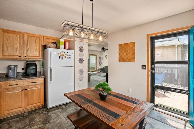 1334 E 13th St, Des Moines, IA 50316 - kitchen with freestanding refrigerator, dark countertops, ceiling fan, and pendant lighting