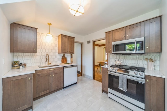 620 48th St, Des Moines, IA 50312 - kitchen featuring appliances with stainless steel finishes, backsplash, decorative light fixtures, and light stone countertops