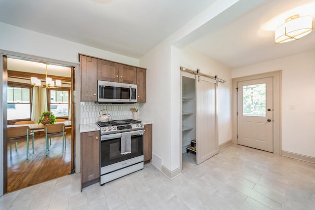620 48th St, Des Moines, IA 50312 - kitchen with stainless steel appliances, a barn door, a chandelier, and backsplash