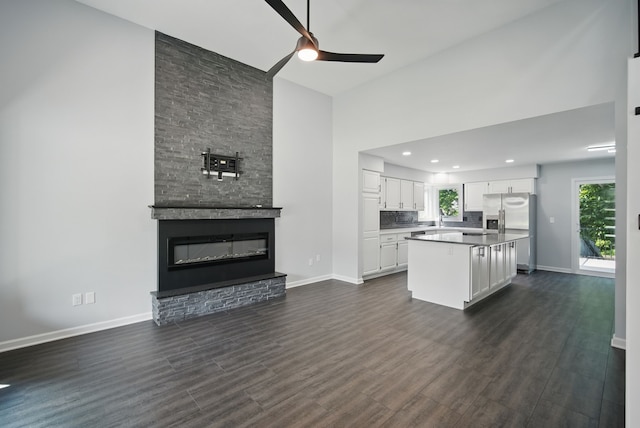 4510 89th St, Urbandale, IA 50322 - living room with a ceiling fan, dark wood-style flooring, a towering ceiling, a stone fireplace, and recessed lighting