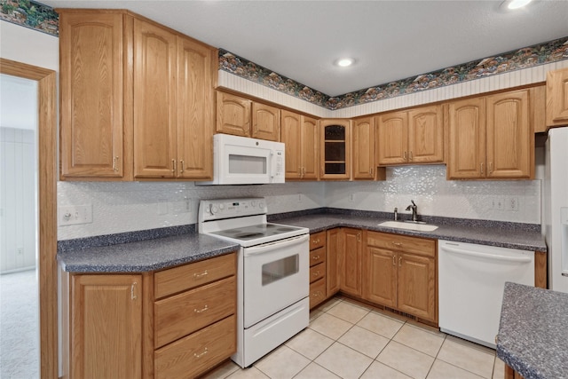 2441 Hull Ave, Des Moines, IA 50317 - kitchen featuring white appliances, dark countertops, glass insert cabinets, light tile patterned floors, and recessed lighting