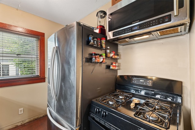 2355 Saylor Rd, Des Moines, IA 50313 - kitchen with black gas range, stainless steel microwave, and wood finished floors