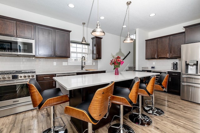 5477 S Prairie View Dr, West Des Moines, IA 50266 - kitchen featuring appliances with stainless steel finishes, light countertops, backsplash, light wood finished floors, and recessed lighting