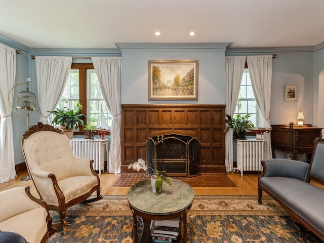 215 Foster Dr, Des Moines, IA 50312 - sitting room featuring radiator heating unit, ornamental molding, a fireplace, and wood finished floors