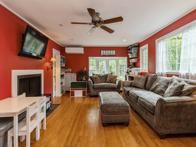215 Foster Dr, Des Moines, IA 50312 - living room featuring healthy amount of natural light, a wall mounted AC, a ceiling fan, light wood finished floors, and crown molding