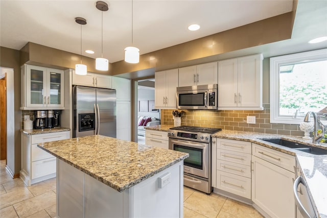 281 58th Ct, West Des Moines, IA 50266 - kitchen with appliances with stainless steel finishes, decorative backsplash, a center island, glass insert cabinets, and white cabinetry