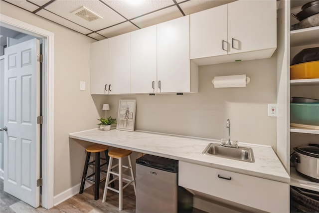 281 58th Ct, West Des Moines, IA 50266 - kitchen with white cabinets, light wood-type flooring, light stone counters, a drop ceiling, and refrigerator