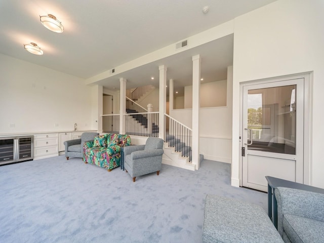 1863 Glen Oaks Dr, West Des Moines, IA 50266 - carpeted living area with stairs, wine cooler, and decorative columns