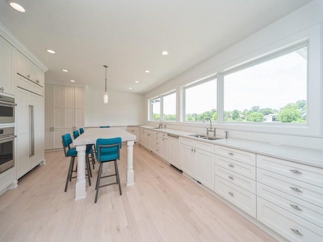 1863 Glen Oaks Dr, West Des Moines, IA 50266 - kitchen with light wood-style flooring, recessed lighting, a breakfast bar, white dishwasher, and white cabinetry