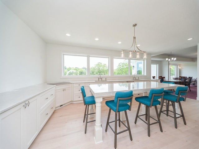 1863 Glen Oaks Dr, West Des Moines, IA 50266 - kitchen with light wood-type flooring, recessed lighting, a kitchen breakfast bar, white cabinetry, and a center island