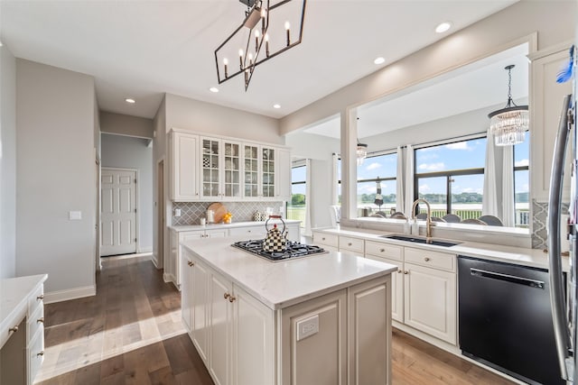 1720 Cedarwood Cir, Clive, IA 50325 - kitchen featuring dishwashing machine, a chandelier, stainless steel gas cooktop, a kitchen island, and decorative backsplash