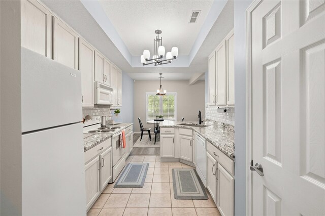 1117 S 52nd St Unit 1705, West Des Moines, IA 50265 - kitchen with white appliances, a chandelier, light tile patterned floors, tasteful backsplash, and a peninsula