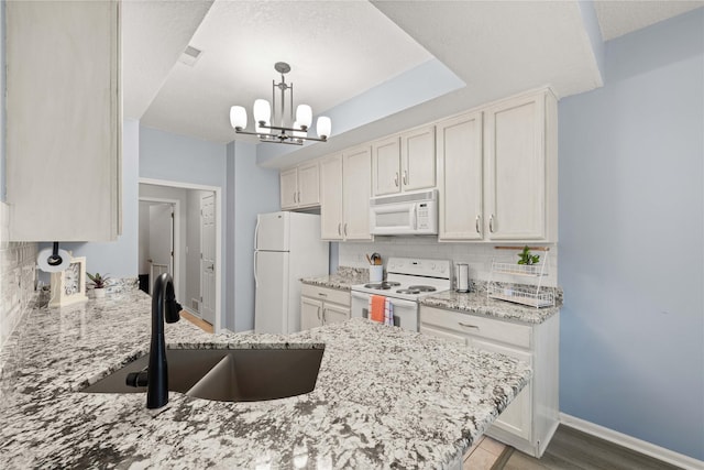 1117 S 52nd St Unit 1705, West Des Moines, IA 50265 - kitchen with white appliances, decorative backsplash, a chandelier, light stone counters, and hanging light fixtures