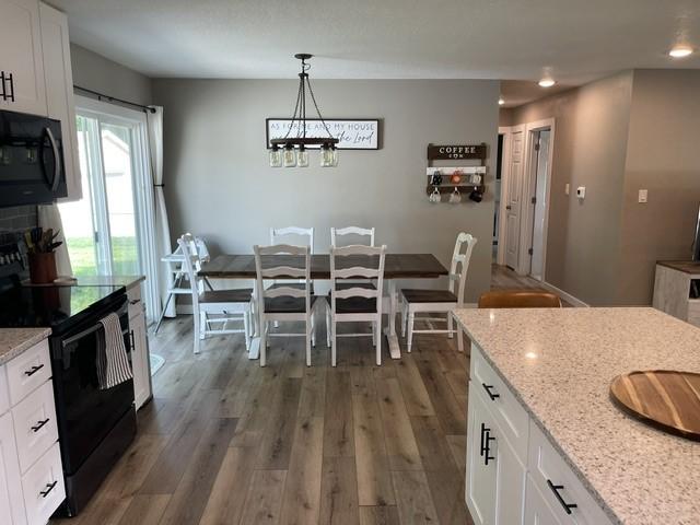 316 NW Linden St, Ankeny, IA 50023 - kitchen with black appliances, white cabinetry, light stone countertops, recessed lighting, and dark wood-style floors