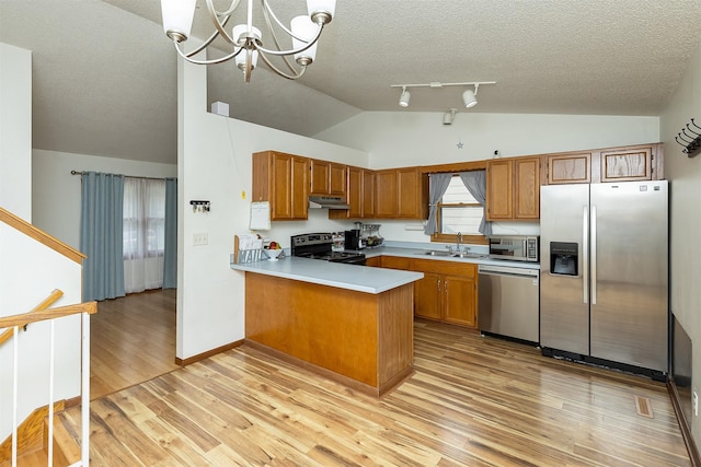 3719 SE 20th St, Des Moines, IA 50320 - kitchen with stainless steel appliances, vaulted ceiling, under cabinet range hood, brown cabinetry, and a peninsula